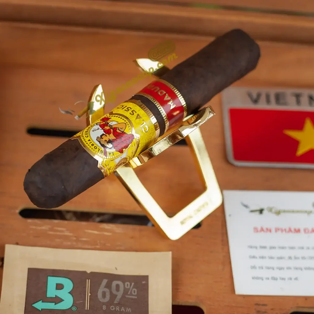 Điếu xì gà lớn đặt cân bằng trên khay gác cigar di động Royal Crown mạ vàng cao cấp.