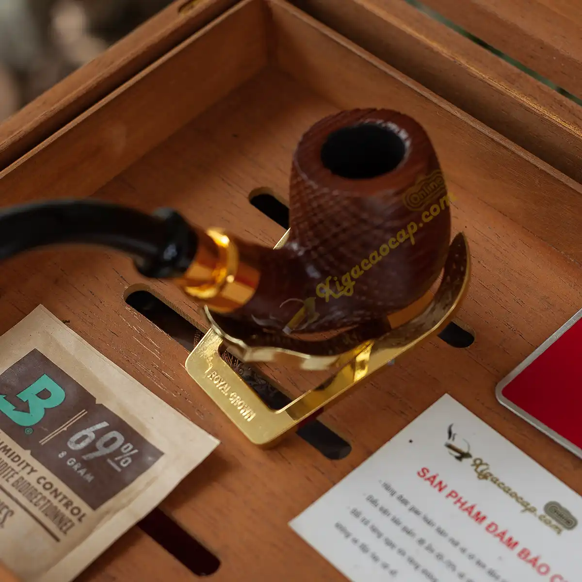 Tẩu thuốc lá sợi đặt vững chãi trên kệ đỡ tẩu chuyên dụng Royal Crown mạ vàng.