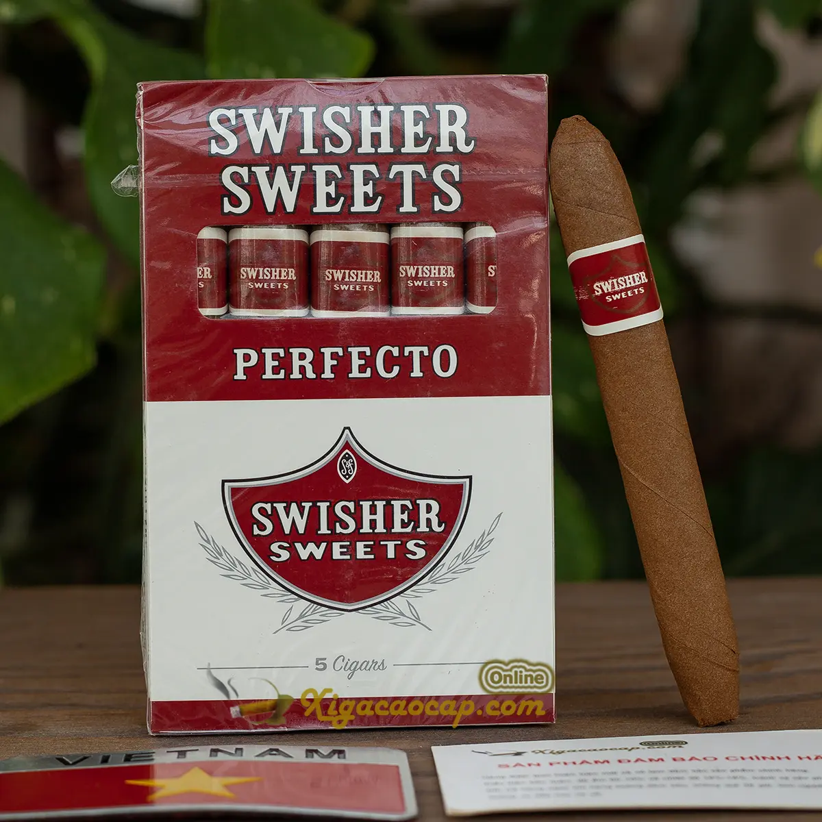 • Hộp xì gà máy Swisher Sweets Perfecto năm điếu được đặt cạnh một điếu lẻ hình dáng thon nằm tách rời bên ngoài.